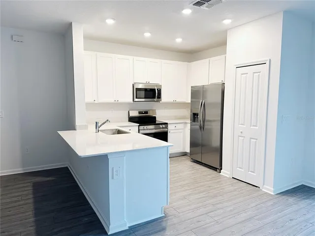 a kitchen with kitchen island a refrigerator stove a sink and dishwasher with wooden floor