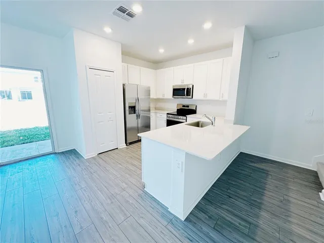 a kitchen with a sink a microwave a refrigerator and wooden floor