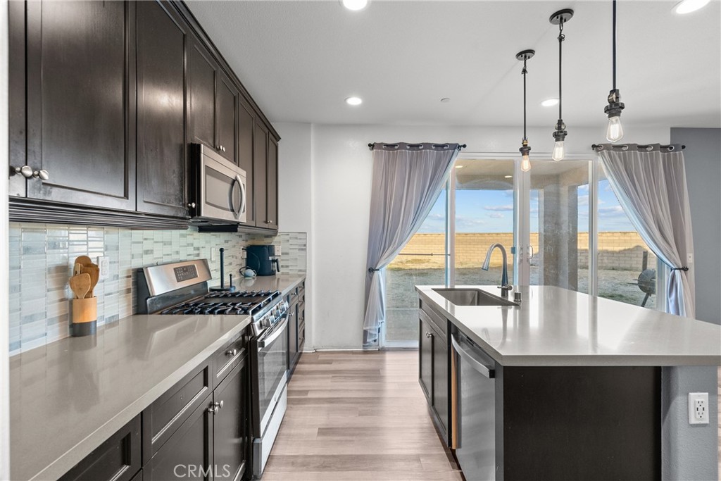 6949 Beale Road Palmdale, CA 93552 - Photo 11 of 32 a kitchen with stainless steel appliances granite countertop a sink a stove and a wooden floors