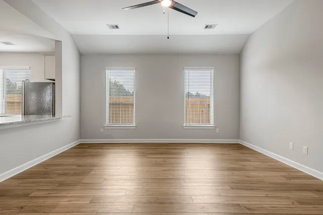 a view of an empty room with wooden floor and a window