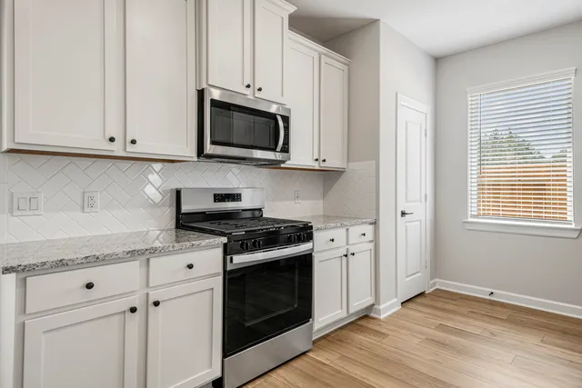 a kitchen with white cabinets and appliances