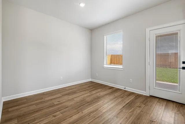 an empty room with wooden floor and windows