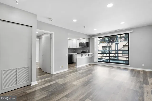 a view of a kitchen with refrigerator and wooden floor