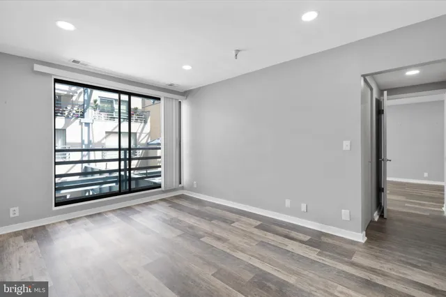 a view of an empty room with a window and wooden floor
