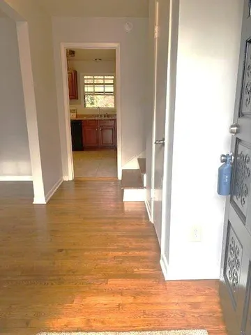 a view of a hallway with wooden floor and a bathroom