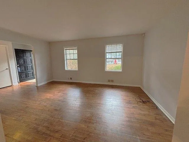 an empty room with wooden floor and windows