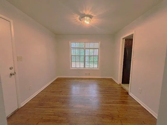 an empty room with wooden floor and window