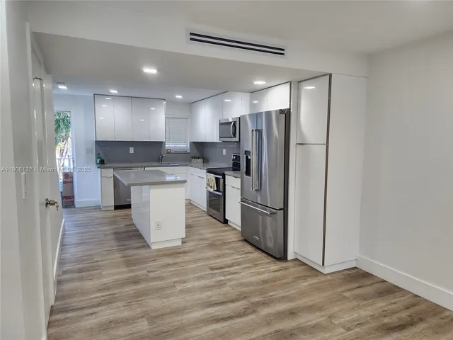 a kitchen with stainless steel appliances granite countertop a refrigerator a sink a stove and oven