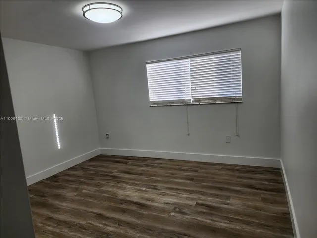 an empty room with wooden floor and entrance