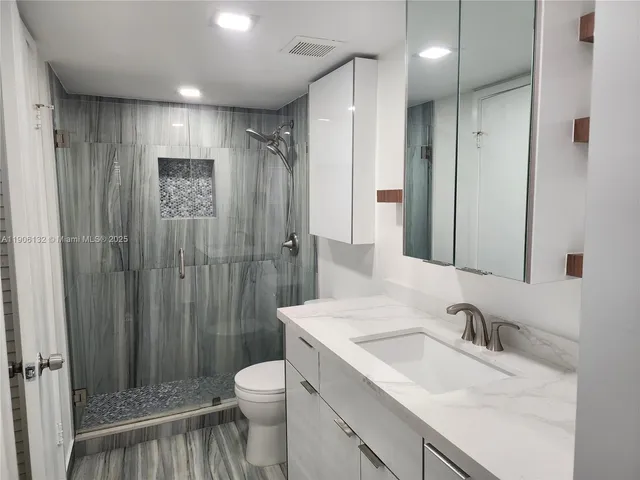 a bathroom with a sink toilet double vanity and shower