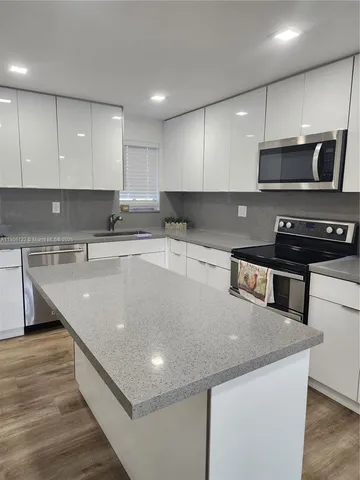 a kitchen with stainless steel appliances granite countertop a sink a stove and a microwave