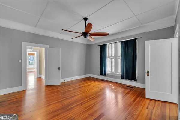 a view of an empty room with wooden floor and a window