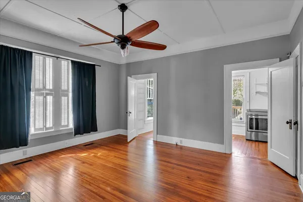 a view of an empty room with wooden floor and a window