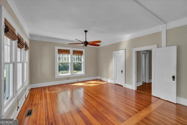 a view of an empty room with wooden floor and a window