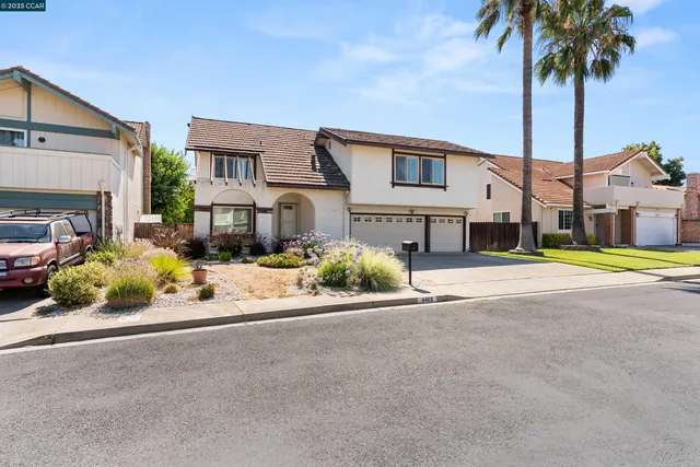 a front view of a house with a garden and parking