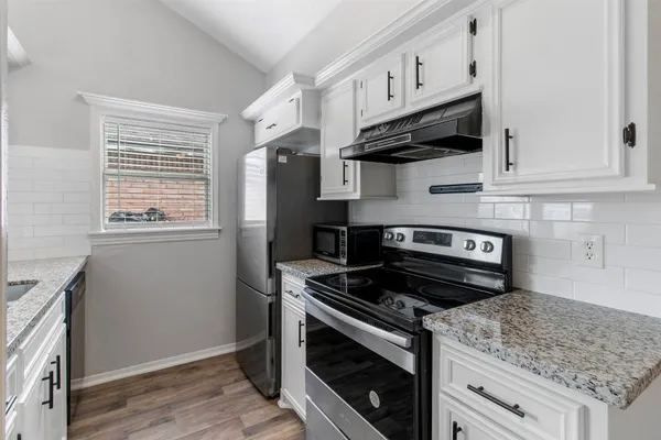 a kitchen with granite countertop cabinets stainless steel appliances and wooden floor