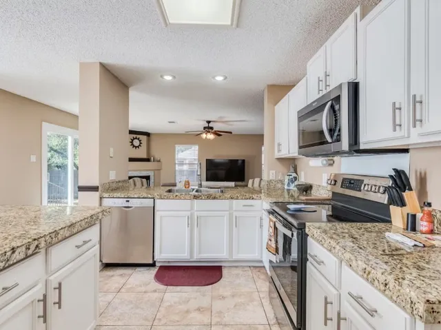 a kitchen with stainless steel appliances granite countertop a stove top oven a sink dishwasher and a refrigerator with the granite countertops