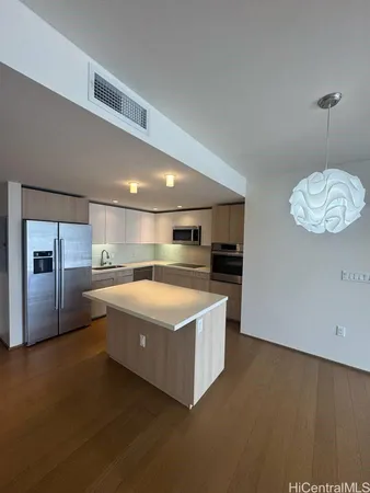 a large kitchen with stainless steel appliances a large counter top a stove and a refrigerator