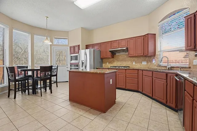 a kitchen with stainless steel appliances granite countertop a stove a sink a dining table and chairs