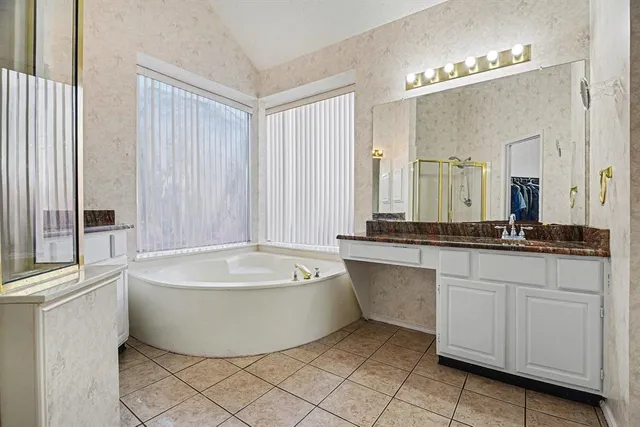 a bathroom with a tub a double vanity sink and mirror