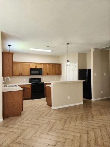 a large kitchen with kitchen island a sink dishwasher a stove and a refrigerator with wooden floor