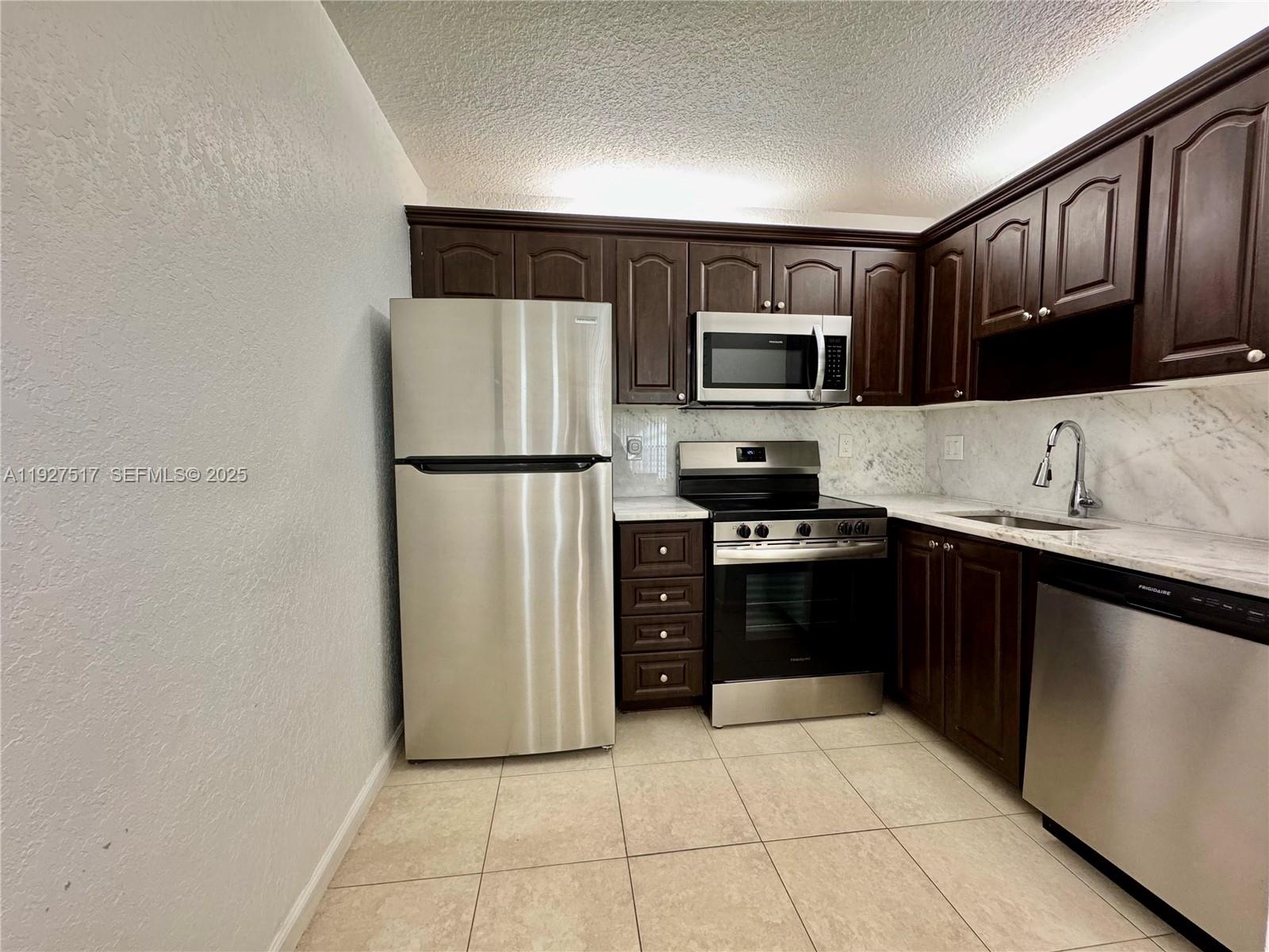 a kitchen with stainless steel appliances granite countertop a refrigerator and a stove top oven