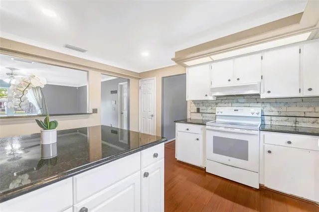 a kitchen with stainless steel appliances granite countertop a sink a stove and white cabinets