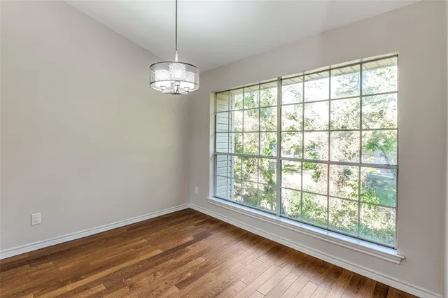 a view of a room with wooden floor chandelier and windows