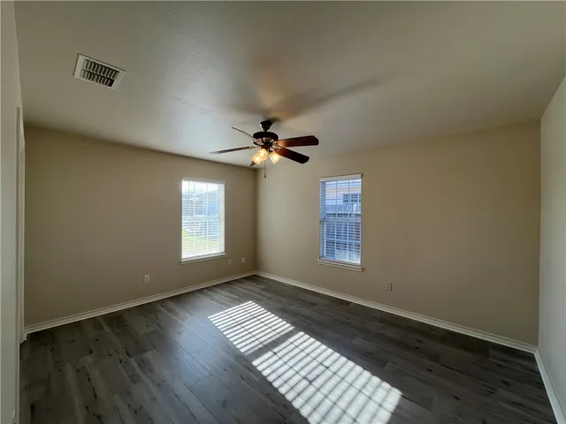 a view of empty room with wooden floor and fan