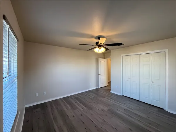 an empty room with wooden floor fan and windows