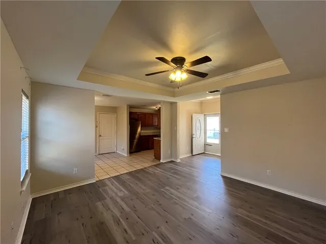 an empty room with wooden floor and a ceiling fan