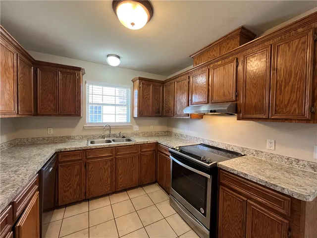 a kitchen with stainless steel appliances granite countertop wooden cabinets a granite counter tops and a sink