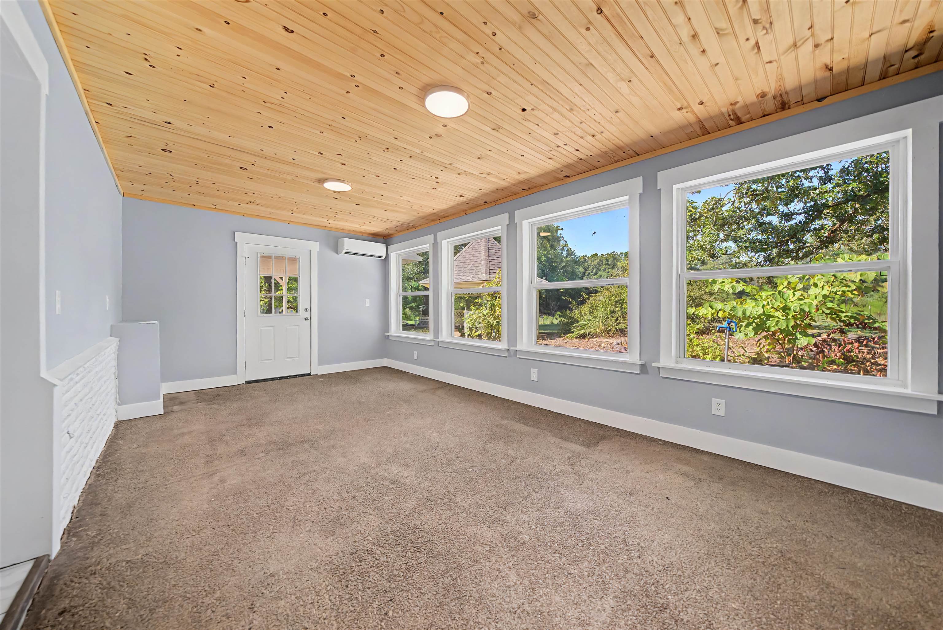 7437 Highway 45 Ramer, TN 38367 - Photo 27 of 36 Wood-finish ceiling, carpeted flooring, multiple windows, white door with glass panels, and a wall-mounted climate control unit