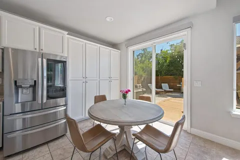 a kitchen with stainless steel appliances granite countertop a refrigerator a stove a sink and white cabinets with wooden floors