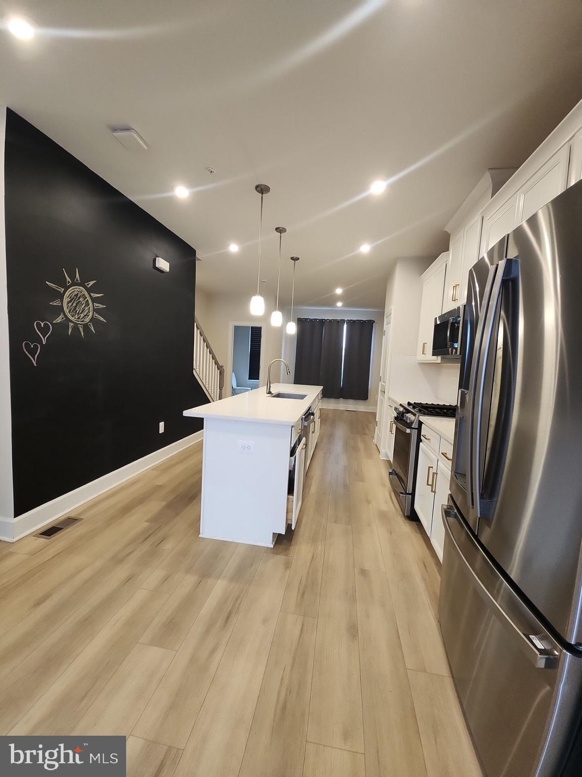 6730 Belcrest Road Hyattsville, MD 20782 - Photo 13 of 30 a kitchen with stainless steel appliances kitchen island granite countertop a refrigerator a stove and a sink with wooden floor
