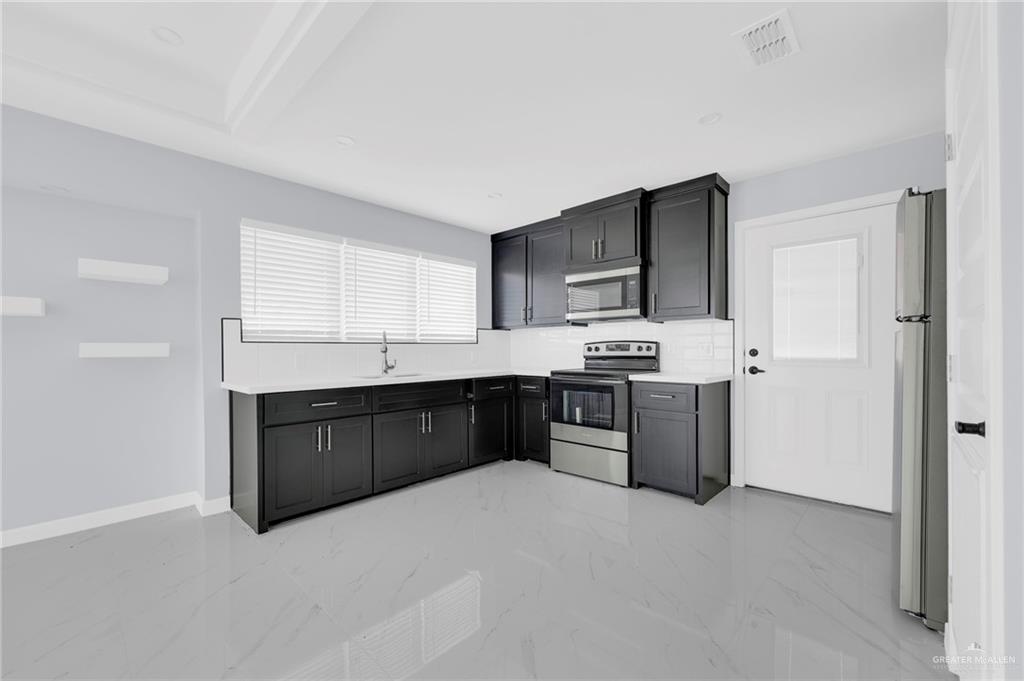 1612 Shadow Creek, Unit 1 Weslaco, TX 78596 - Photo 7 of 12 a kitchen with stainless steel appliances granite countertop a stove a sink dishwasher a refrigerator and a oven