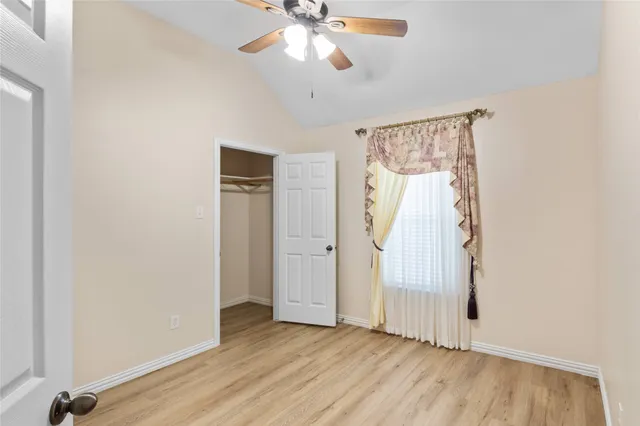 an empty room with wooden floor fan and windows