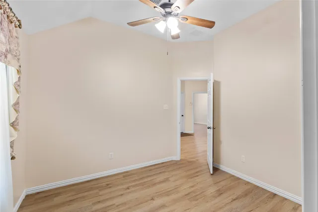 an empty room with wooden floor and fan