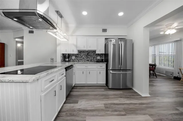 a kitchen with cabinets wooden floor and stainless steel appliances