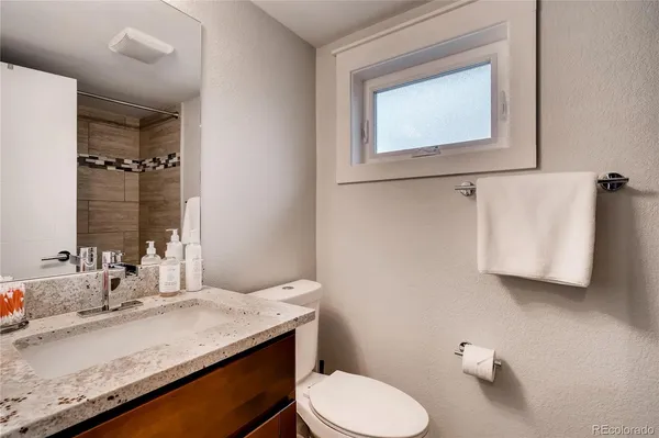a bathroom with a granite countertop toilet sink and mirror