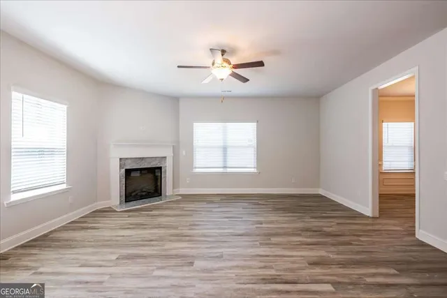 a view of an empty room with wooden floor fireplace and a window