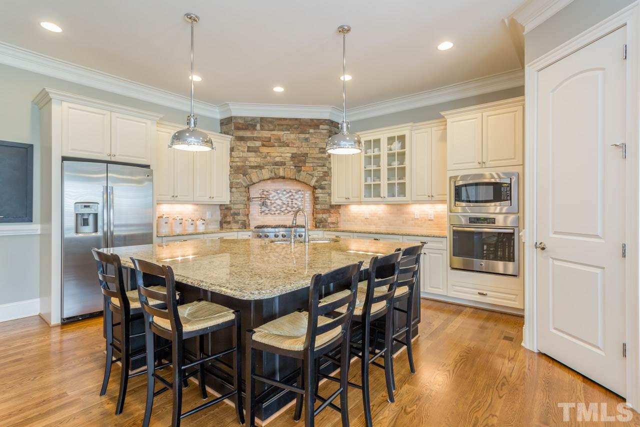 5012 Pomfret Point Raleigh, NC 27612 - Photo 6 of 25 When you walk into the kitchen, be prepared to say, "WOW"! This kitchen is exceptional! It features an expansive central island with stunning pendant lights, custom cabinets, and a gas cook top framed with a stone surround.