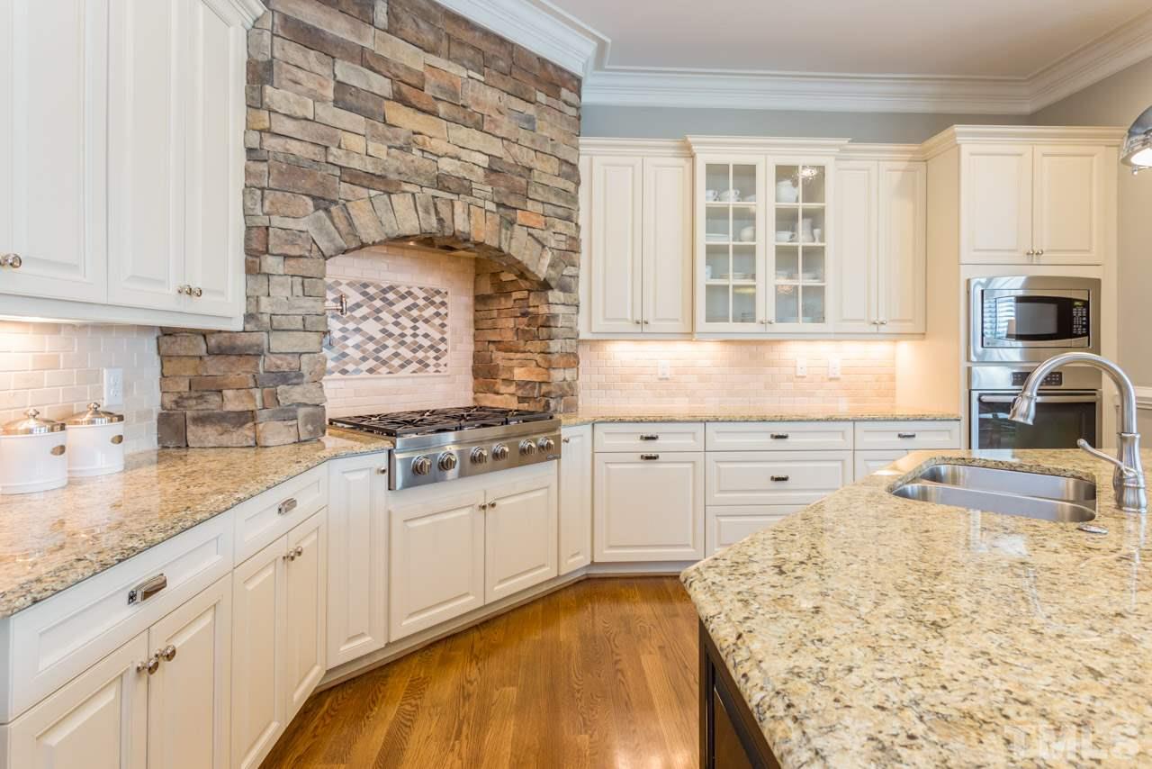 5012 Pomfret Point Raleigh, NC 27612 - Photo 7 of 25 The stone surround creates a cozy setting for meal preparation and entertaining. Additional features include stainless appliances, granite counter tops, crown molding, a cabinet with double glass doors, and crown molding.