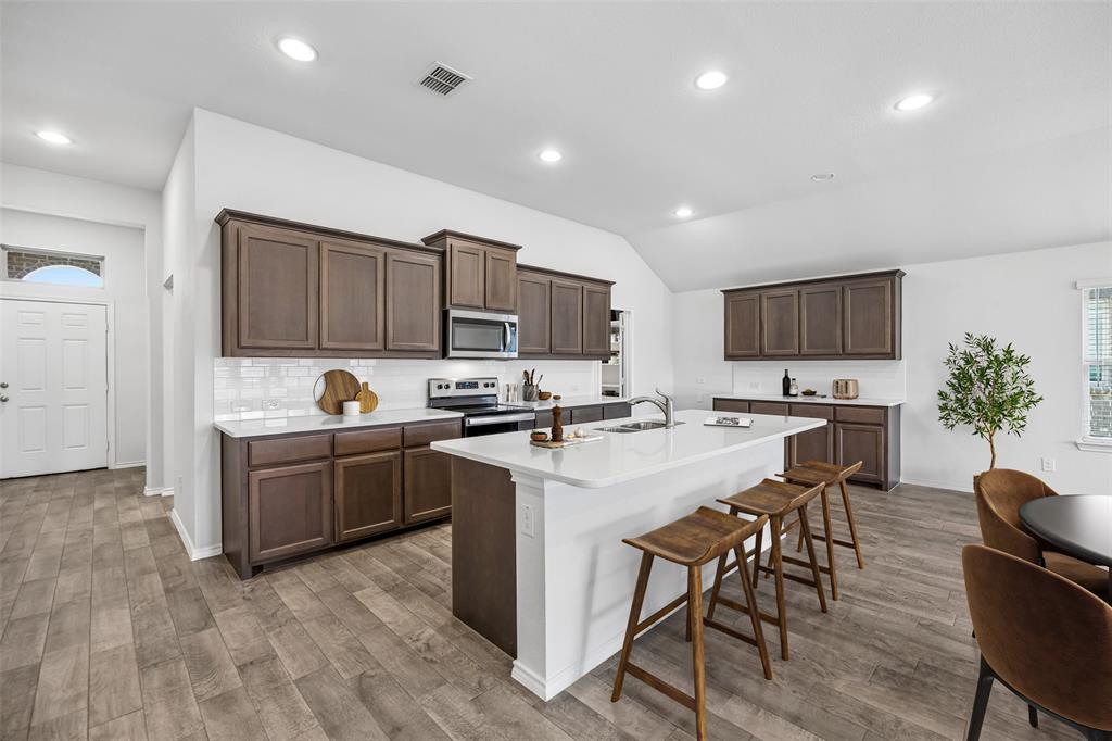 3807 Dogwood Road Melissa, TX 75454 - Photo 3 of 38 a kitchen with a sink a stove a refrigerator cabinets and a dining table with chairs