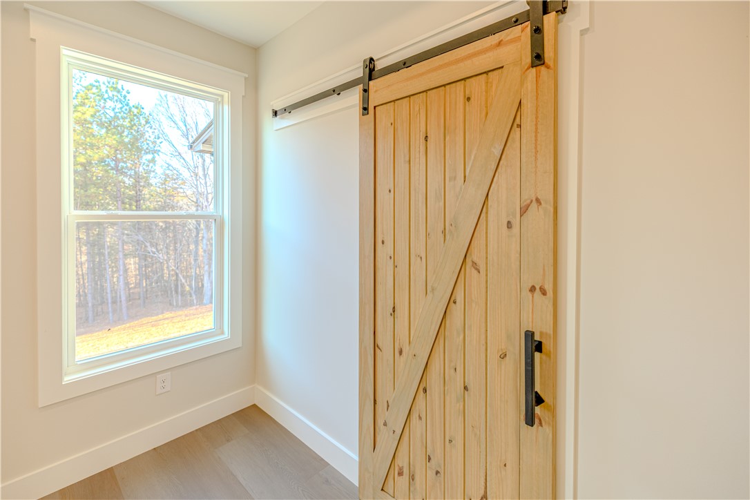 1409 Stonehurst Road Anderson, SC 29621 - Photo 17 of 37 This interior features a wooden barn door and a window offering views of the natural landscape.