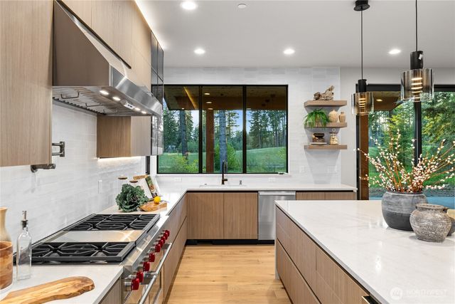 a kitchen with kitchen island a large counter top a stove a sink dishwasher and a dining table with garden view