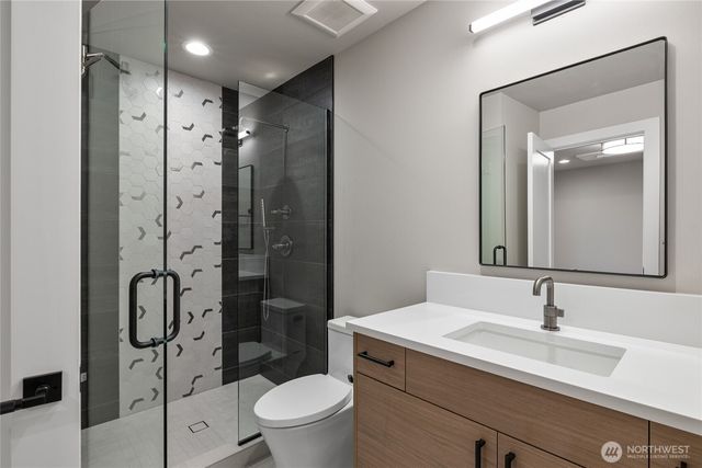 a bathroom with a shower sink vanity mirror and toilet