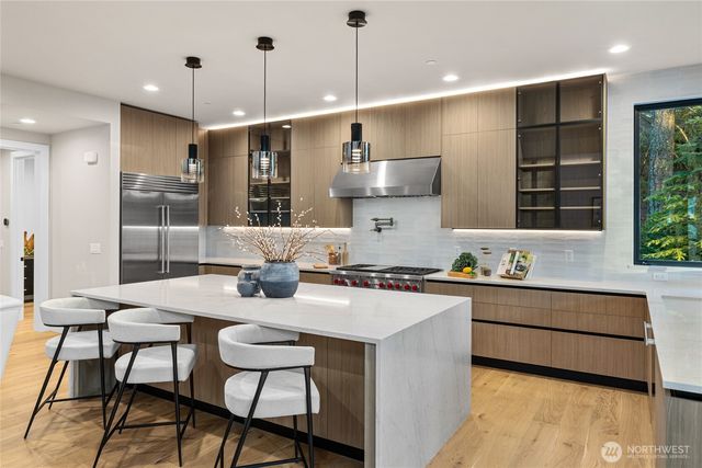 a kitchen with granite countertop a stove a sink a refrigerator a dining table and chairs