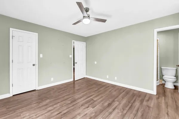 an empty room with wooden floor and a ceiling fan
