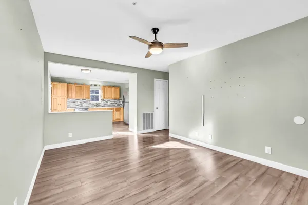 a view of an empty room with wooden floor and a window